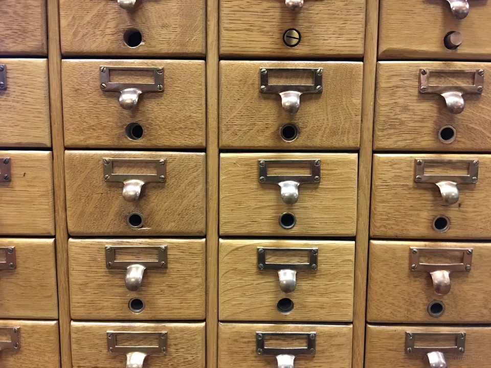 Rows of oak library card-catalogue drawers with brass label holders and pulls