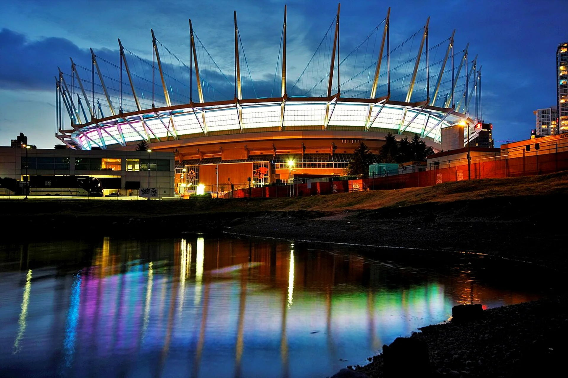 BC Place stadium in Vancouver lit up at dusk over False Creek