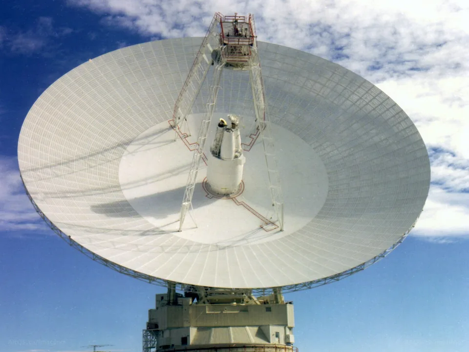 Front view of the 70-metre Deep Space Network antenna at Goldstone in California's Mojave Desert against a blue sky with clouds