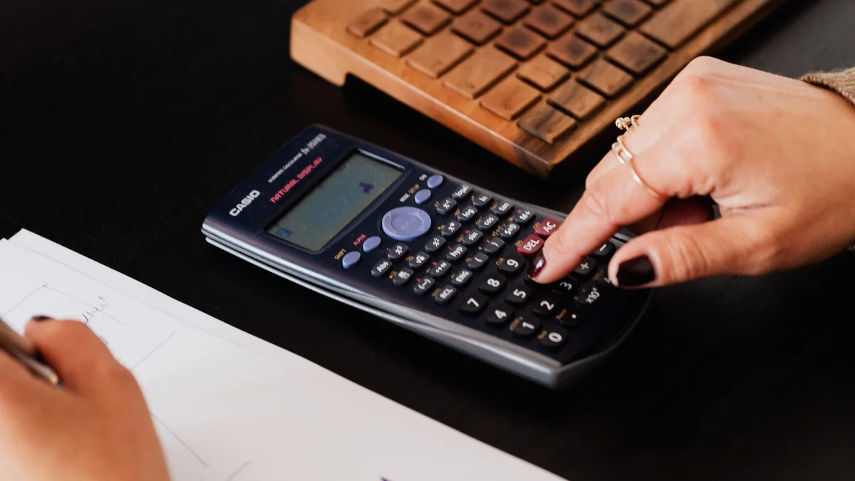 An open notebook, laptop and rolled plans on a consultant's desk