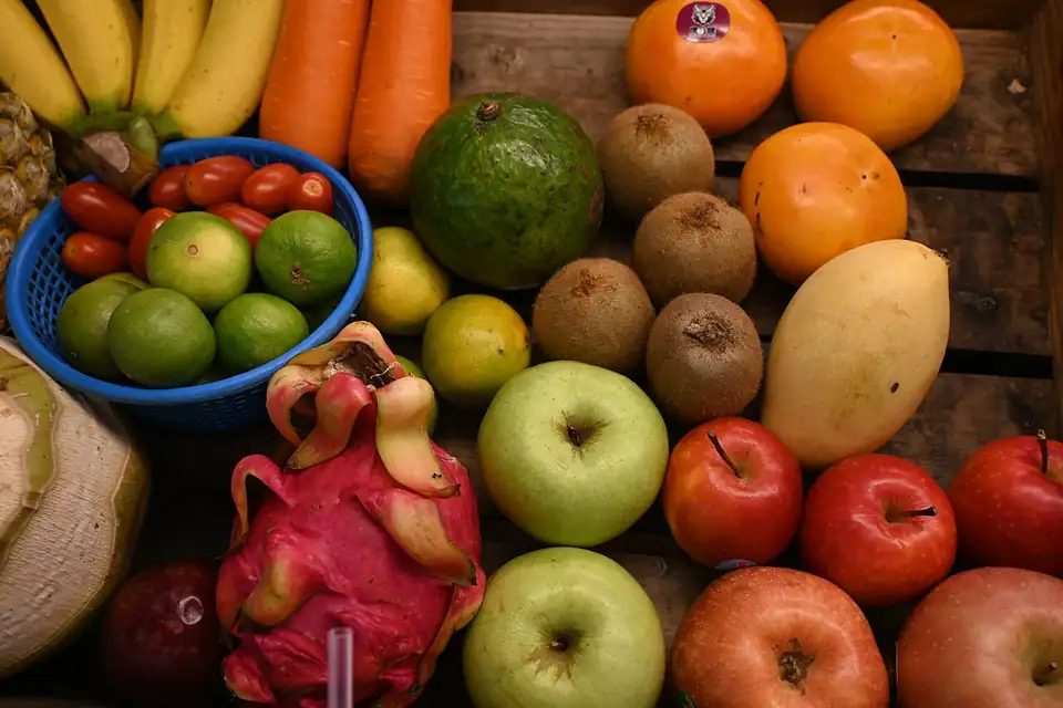 Photo: DFC 2197 A colorful assortment of fresh fruits and vegetables - apples mango dragon fruit kiwis limes bananas and more - arranged on a wooden crate