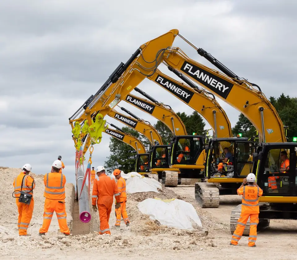 Workers lower pipe into a trench during pipeline construction (file photo, United Kingdom)