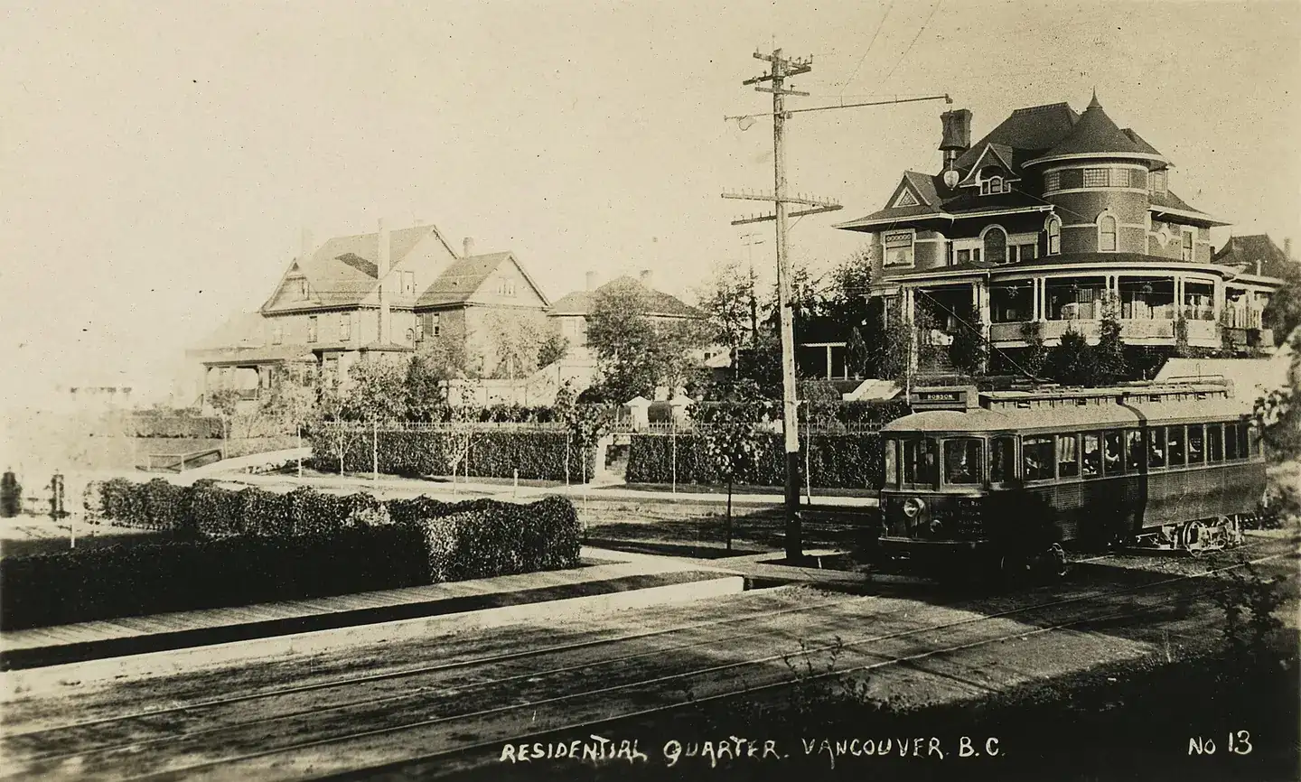View of neighborhood with a row of houses including a Queen Anne Revival with a street car in front