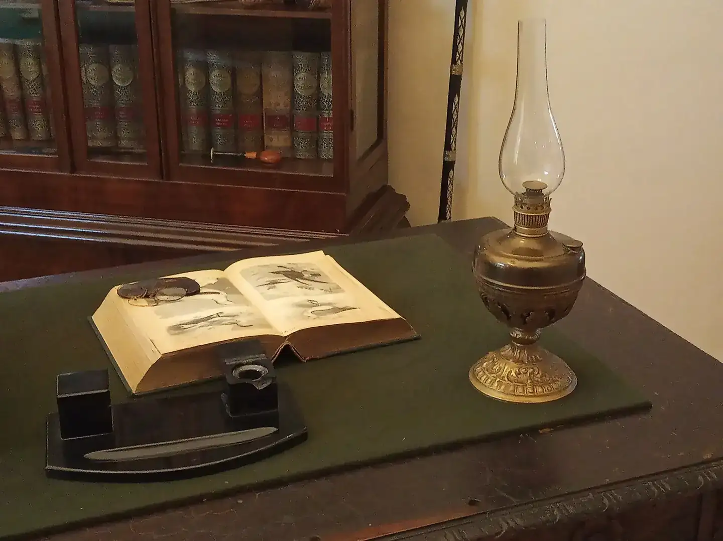 An open book and oil lamp on a desk in a museum study in Michalovce, Slovakia