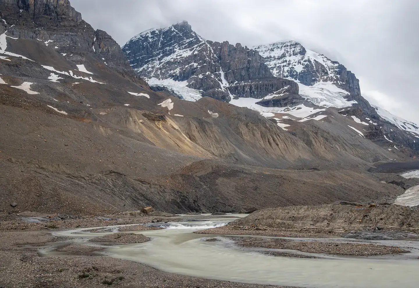 Meltwater flowing directly from the terminus of the Athabasca Glacier, with Mount Andromeda visible in the background