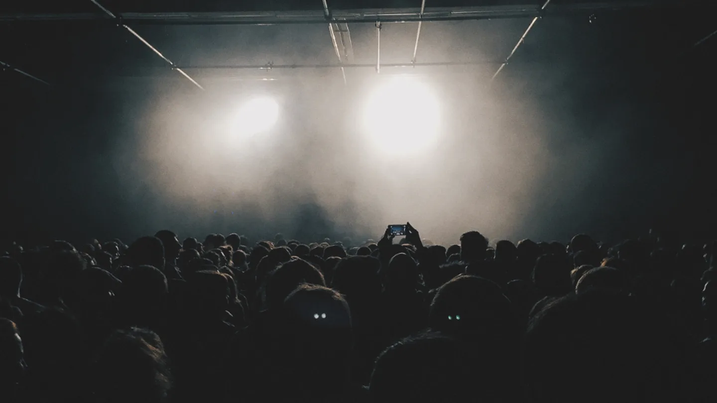Stage lights glowing over a festival crowd at night