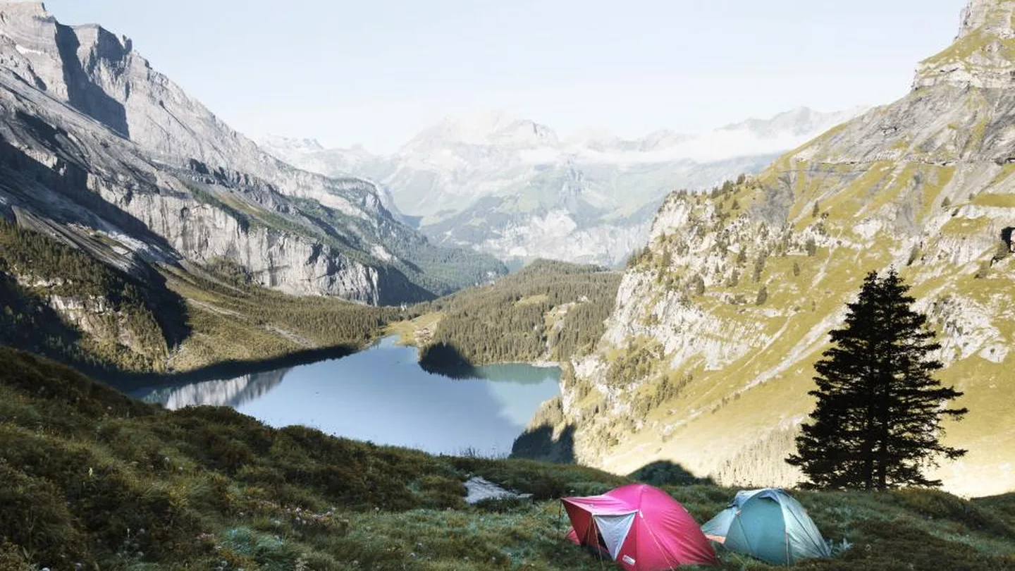 Colourful tents pitched above an alpine lake